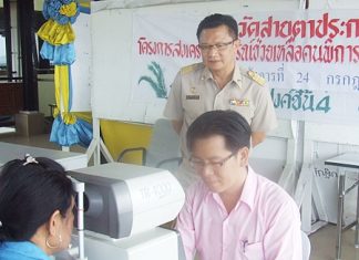 Deputy Mayor Verawat Khakhay looks on as Pawit Chotthonawuth, owner of Mahanakhorn spectacle shop, performs a free eye exam.